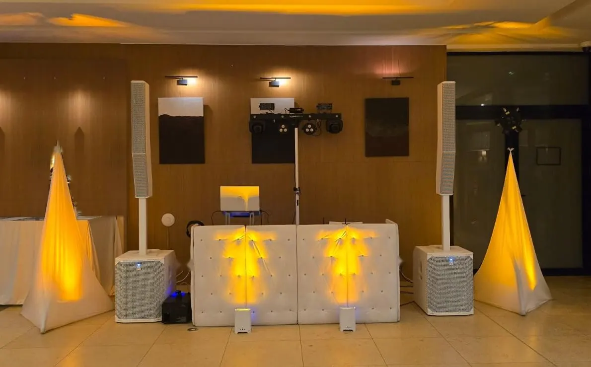 Installation DJ tout en blanc pour un mariage : cabine capitonnée, colonnes et lumières dorées