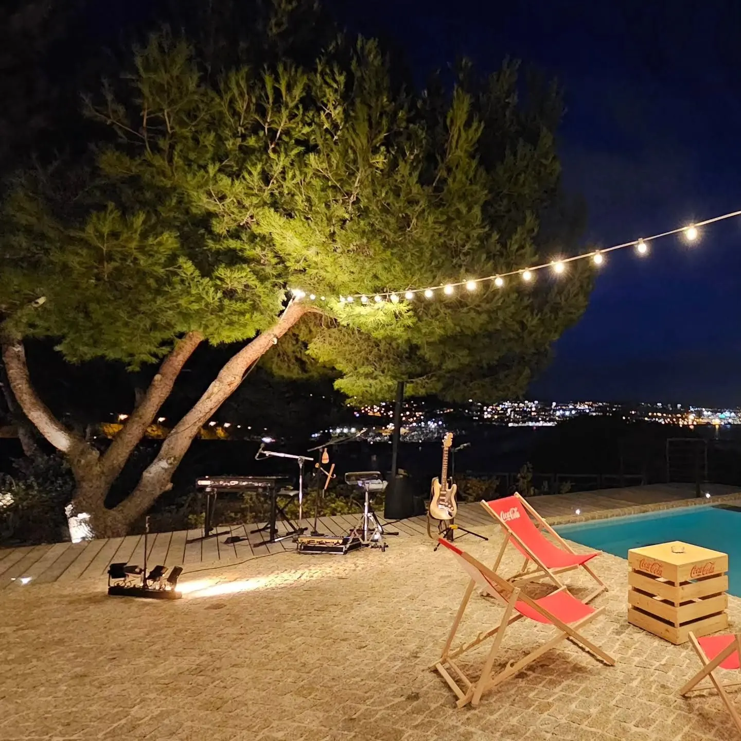 Scène de nuit sous les pins et les guirlandes, au bord de la piscine d'une villa